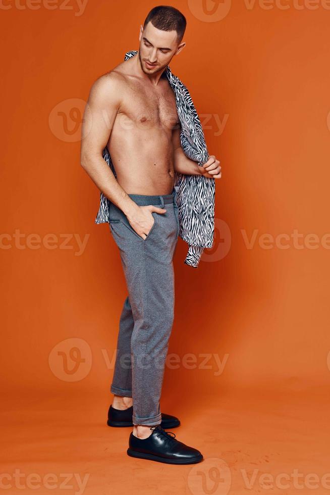 bonito homem dentro camisa nu tronco posando moda laranja fundo foto
