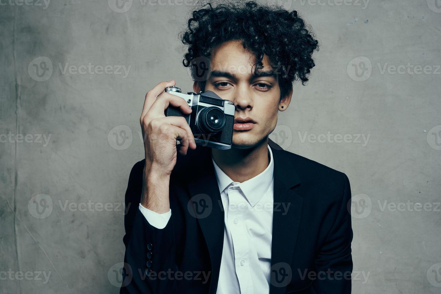 fotógrafo com Câmera dentro de casa em cinzento fundo e Jaqueta cachos camisa modelo foto