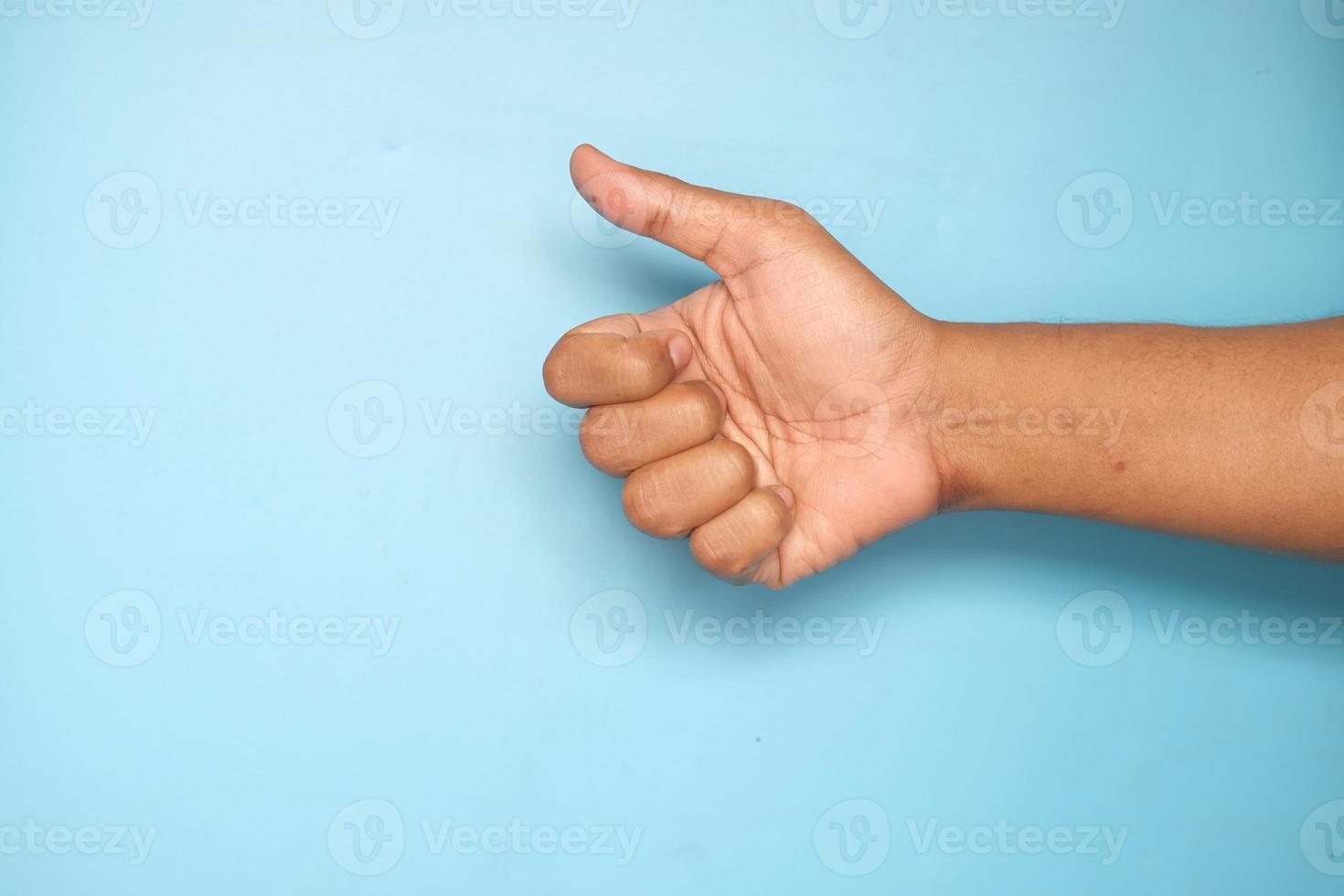 mão mostrando um polegar para cima em fundo azul foto