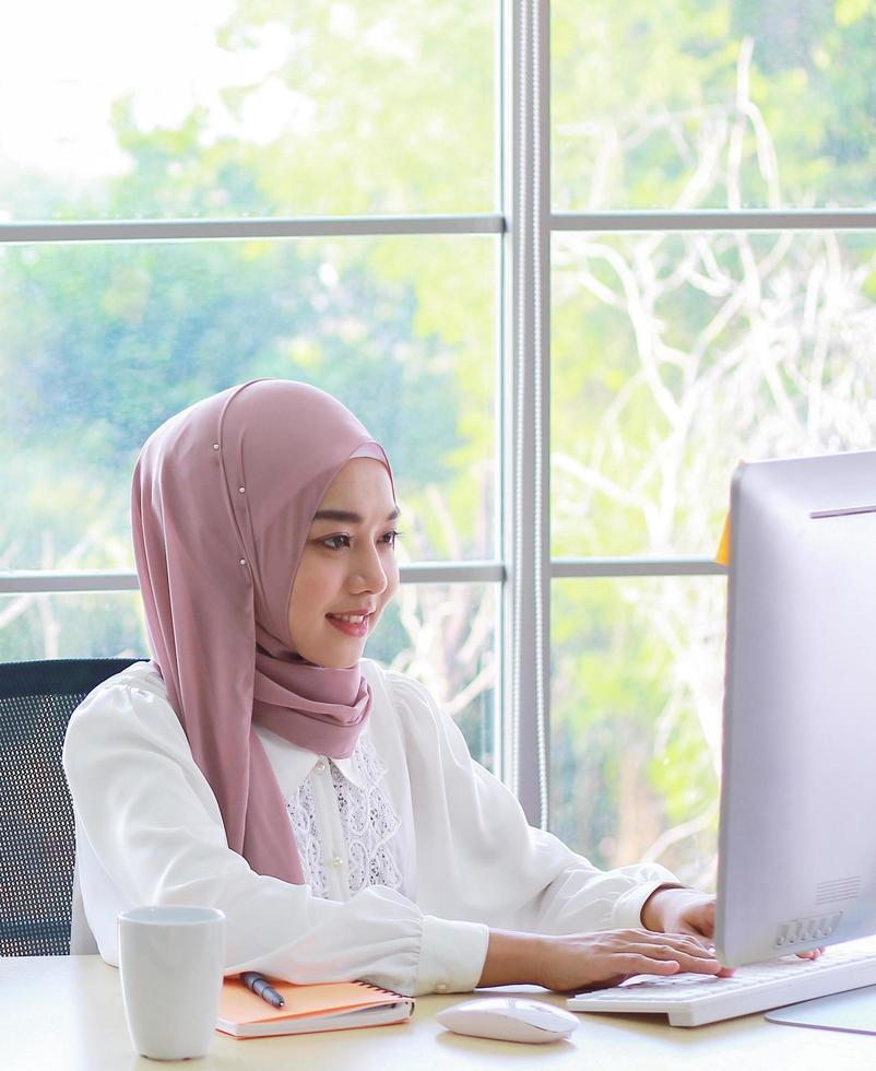 linda empresária muçulmana trabalhando feliz no escritório foto