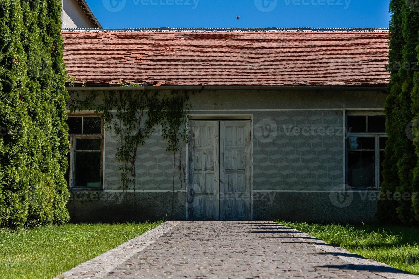 beco do árvores conduzindo para a casa com velho portas foto