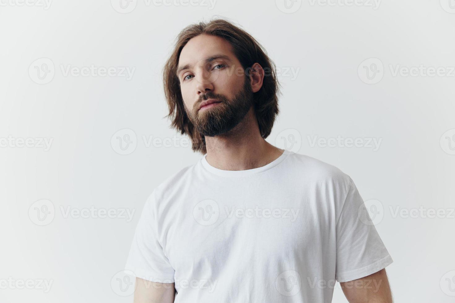 retrato do uma homem com uma Preto Grosso barba e grandes cabelo dentro uma branco camiseta em uma branco isolado fundo emoção do tristeza e anseio foto