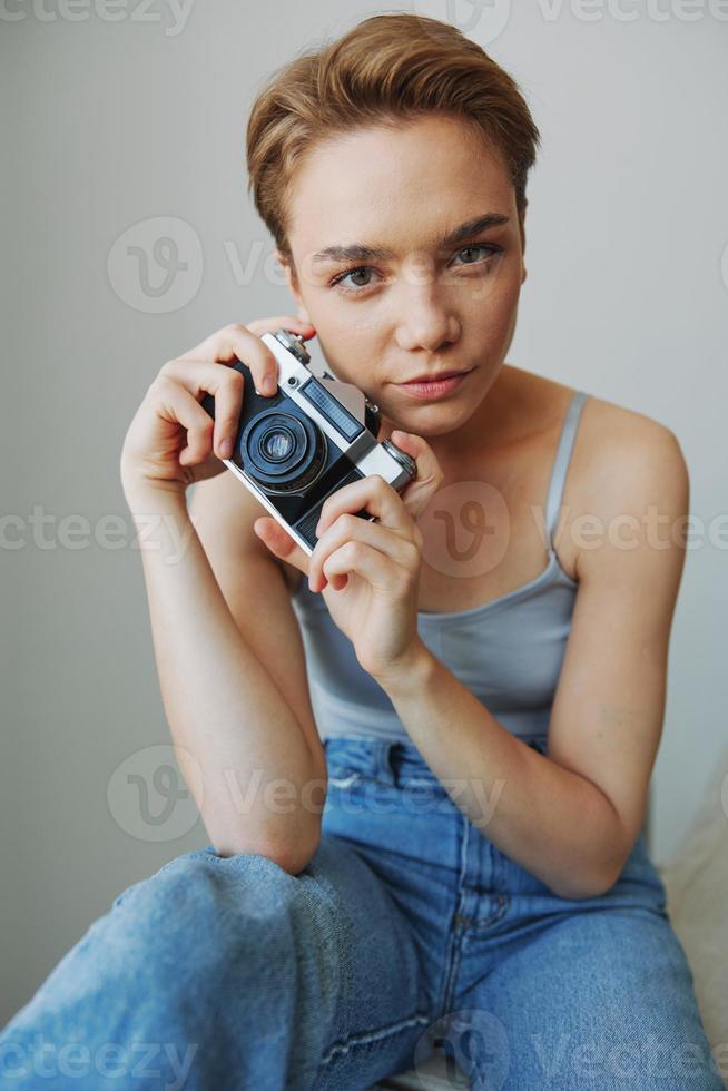 mulher fotógrafo tiroteio dentro estúdio em velho filme Câmera às casa em sofá retrato, branco fundo, livre cópia de espaço, freelance fotógrafo foto