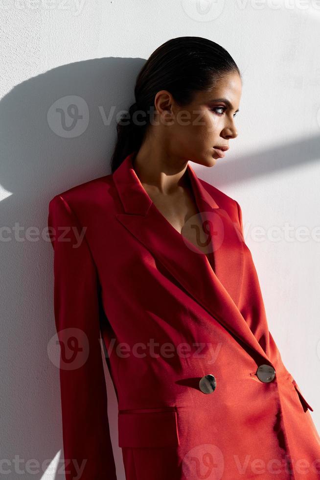 retrato do uma mulher dentro uma vermelho Jaqueta em uma luz fundo Maquiagem morena foto