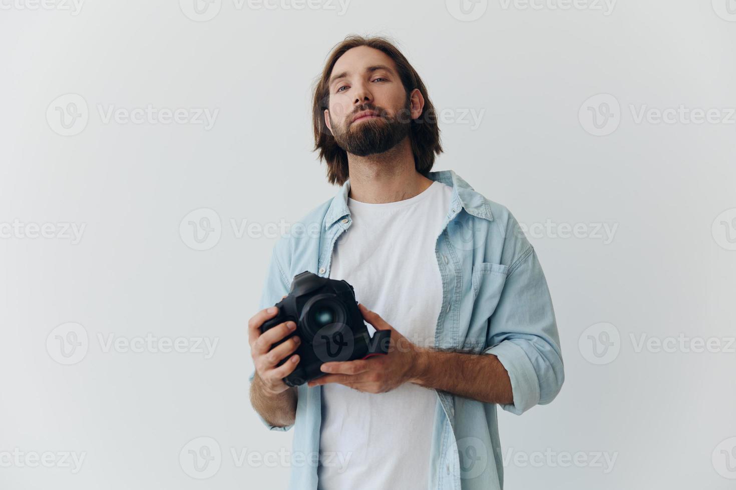 homem hipster fotógrafo dentro uma estúdio contra uma branco fundo segurando uma profissional Câmera e configuração isto acima antes tiroteio. estilo de vida trabalhos Como uma freelance fotógrafo foto
