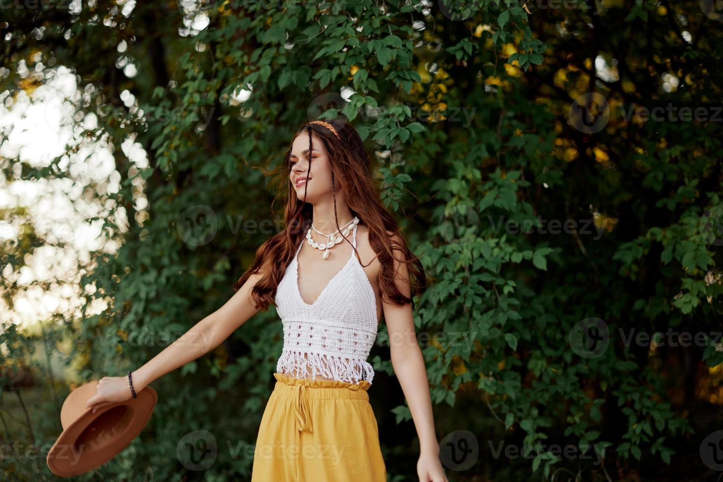 uma mulher dentro ecológico roupas dentro uma hippie Veja danças dentro natureza dentro a parque e sorrisos às a mundo. a conceito do harmonia com a corpo e a em torno da natureza foto