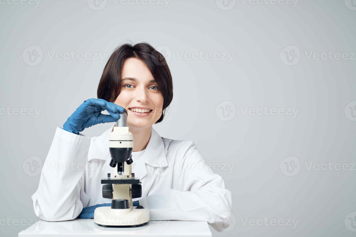 fêmea laboratório assistente olhando através uma microscópio diagnóstico pesquisa Ciência foto