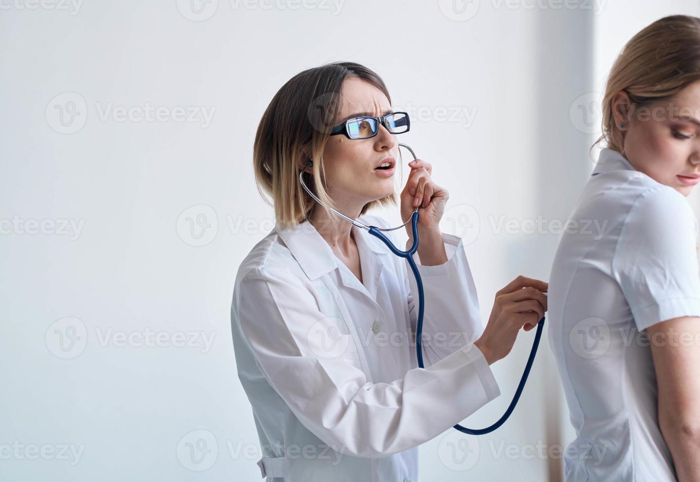 médico dentro uma médico vestido com uma estetoscópio examina uma paciente em uma luz fundo foto