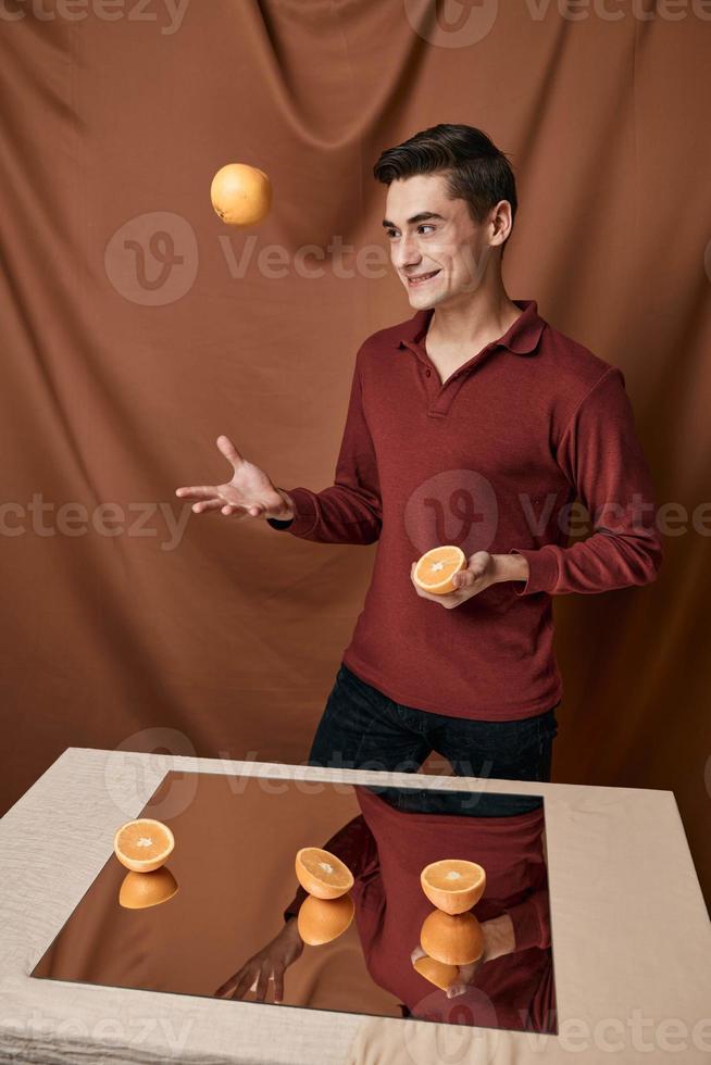 engraçado homem dentro uma vermelho camisa sorteio a laranja perto a espelho foto