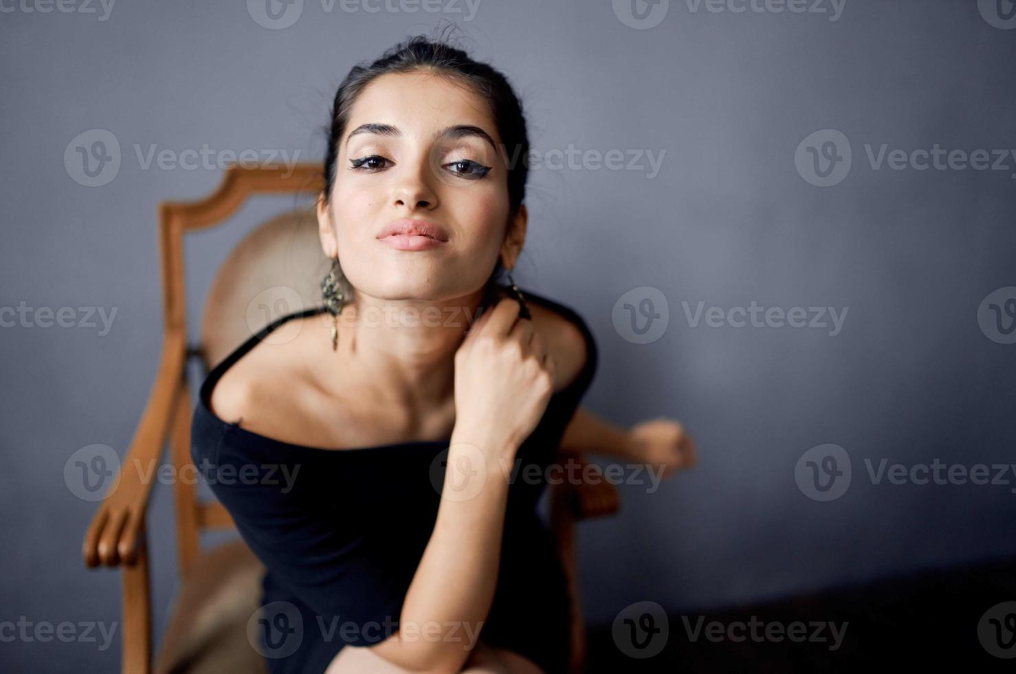 bonita mulher dentro uma Preto vestir perto a cadeira luxo moda isolado fundo foto