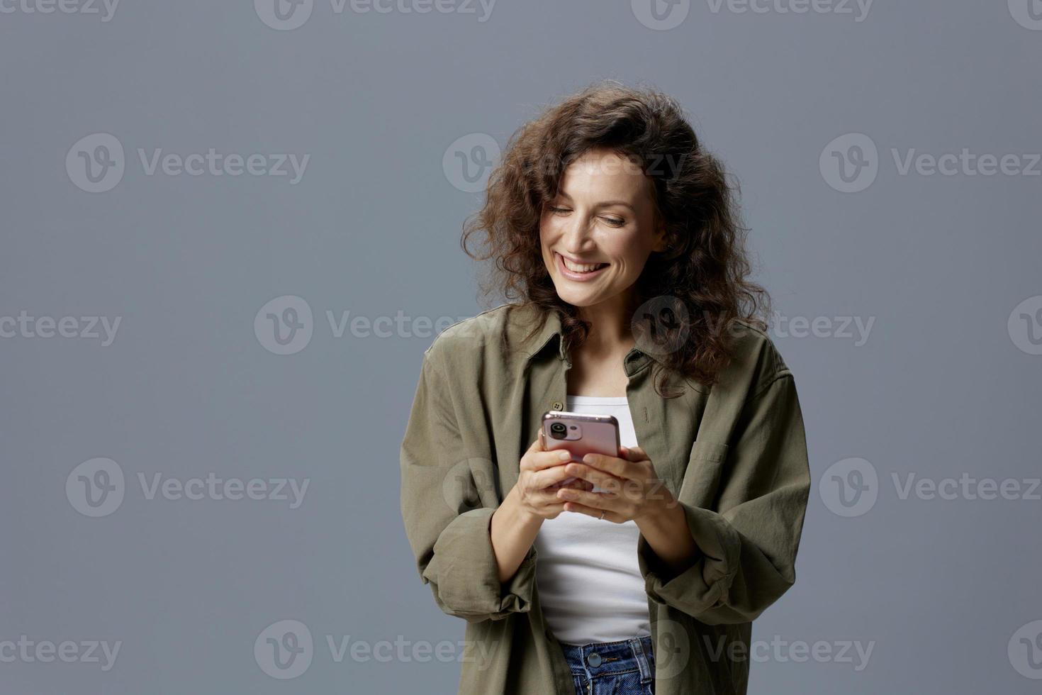 feliz alegre sorridente encaracolado lindo mulher dentro casual cáqui verde camisa conversando com namorado usando telefone posando isolado em sobre cinzento azul fundo. social meios de comunicação influenciador conceito. cópia de espaço foto