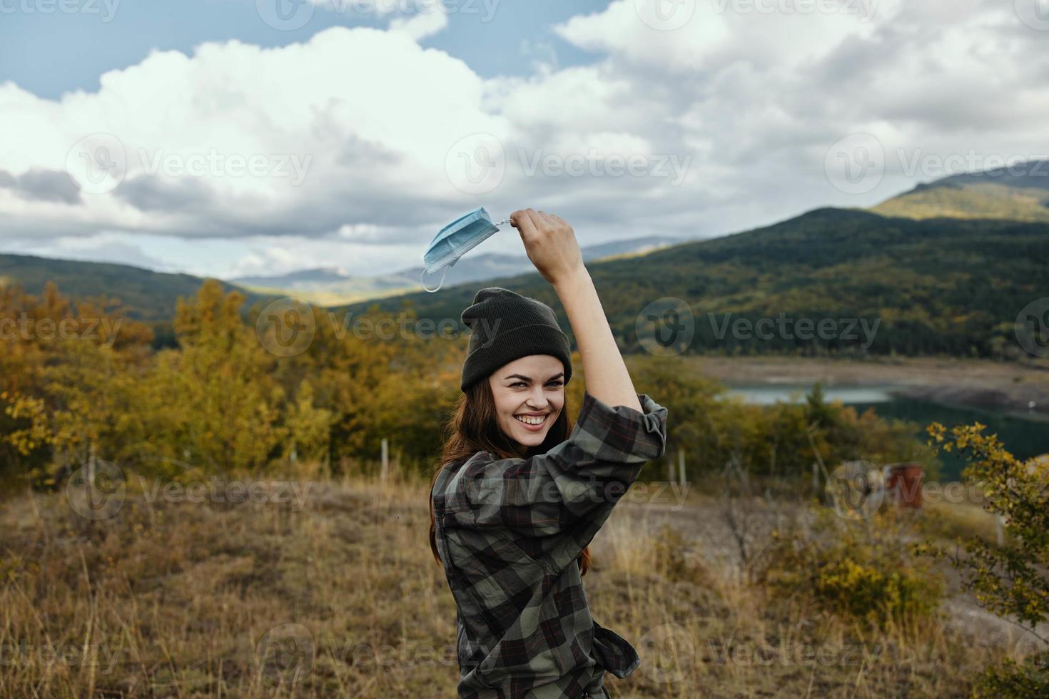 alegre mulher com uma médico mascarar dentro dela mão dentro a floresta seco Relva montanhas natureza foto