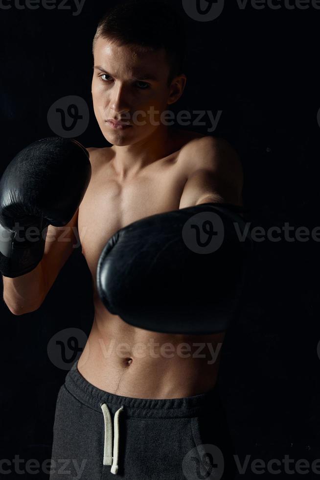 atleta dentro Preto boxe luvas em uma Sombrio fundo fisiculturista ginástica modelo foto