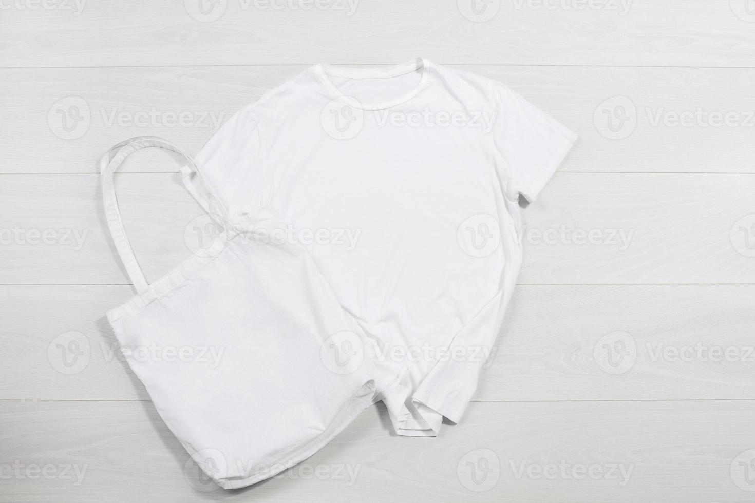 brincar camiseta branco comprador Bolsa em madeira fundo. topo Visão cópia de espaço compras eco reutilizável bolsa. modelo em branco algodão material tela de pintura camiseta pano. esvaziar brincar camisa de praia tecido foto