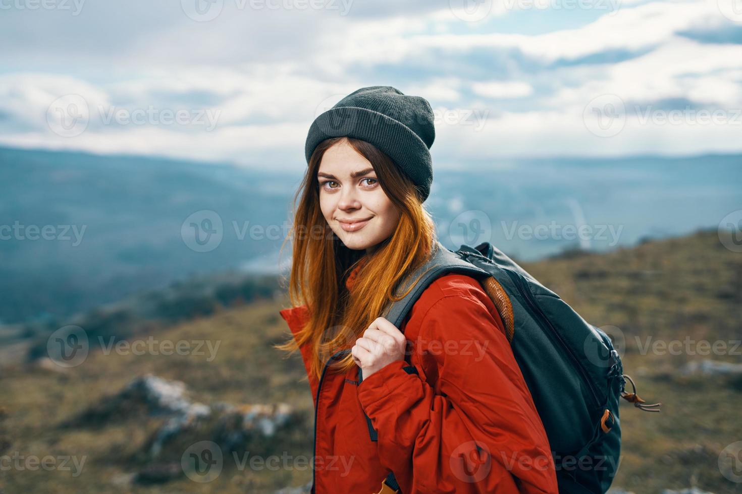 retrato do uma viajante dentro uma vermelho Jaqueta e chapéu e com uma mochila ao ar livre dentro a montanhas fresco ar foto