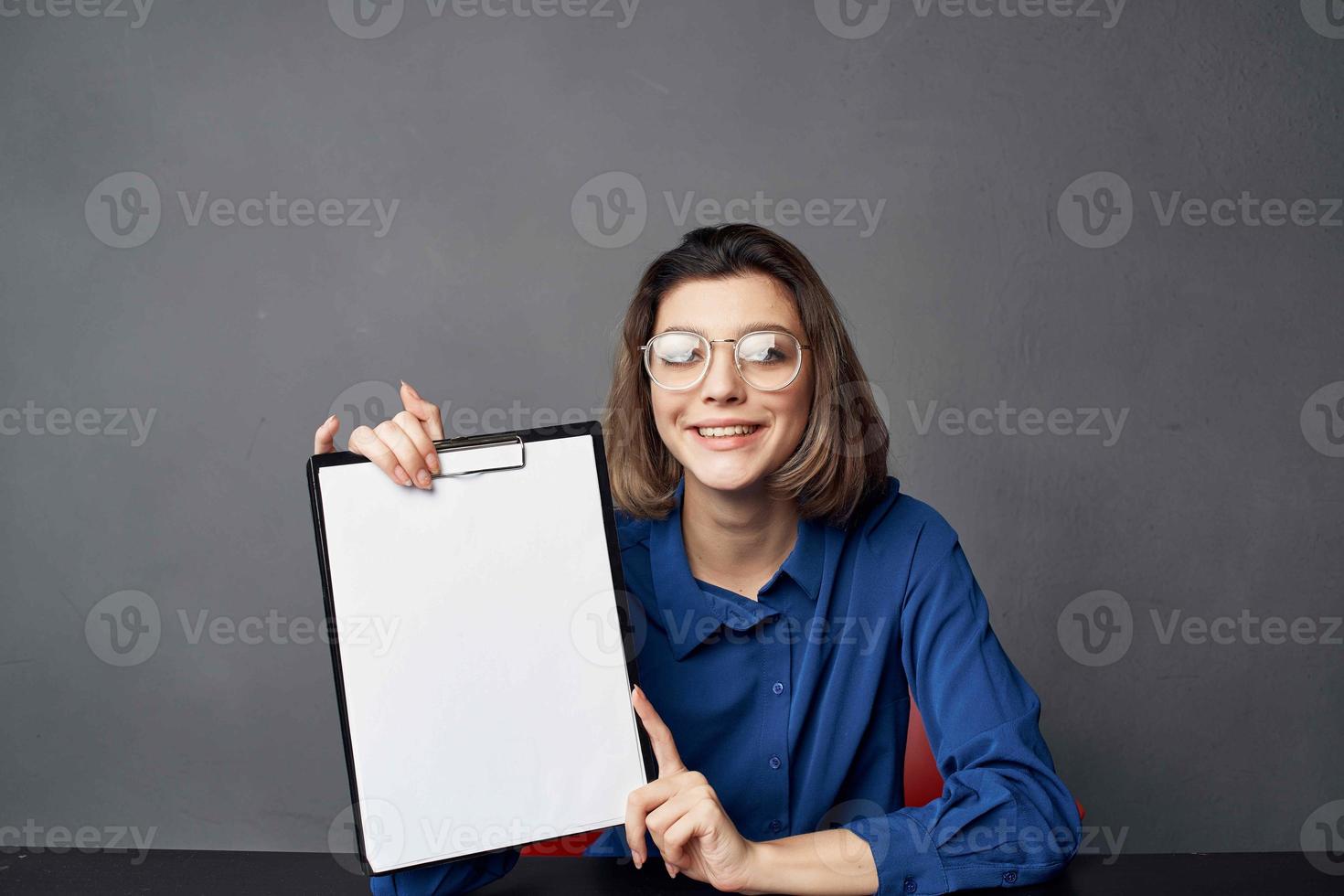 o negócio mulher com óculos senta às a mesa enquanto segurando cópia de espaço foto