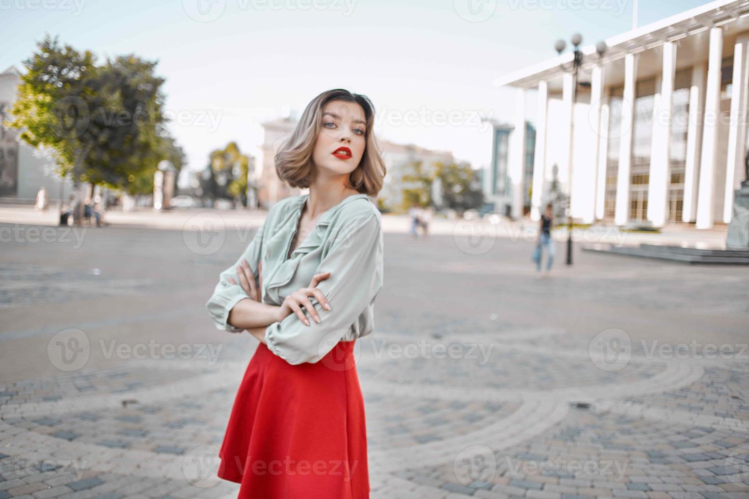alegre mulher dentro uma vermelho saia em a quadrado dentro a cidade andar foto