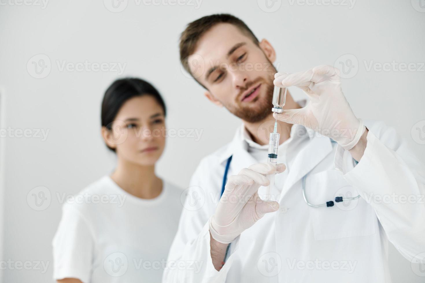 masculino médico com uma seringa dentro dele mão e uma fêmea paciente dentro a fundo vacinação foto