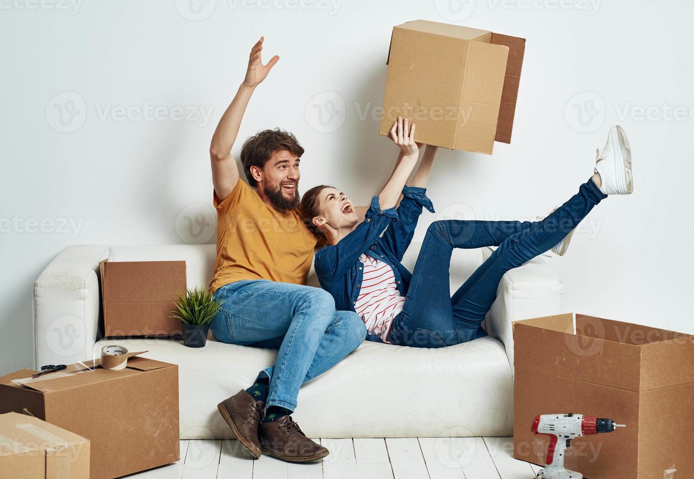 família jovem casal em a sofá Diversão comovente caixas com coisas foto