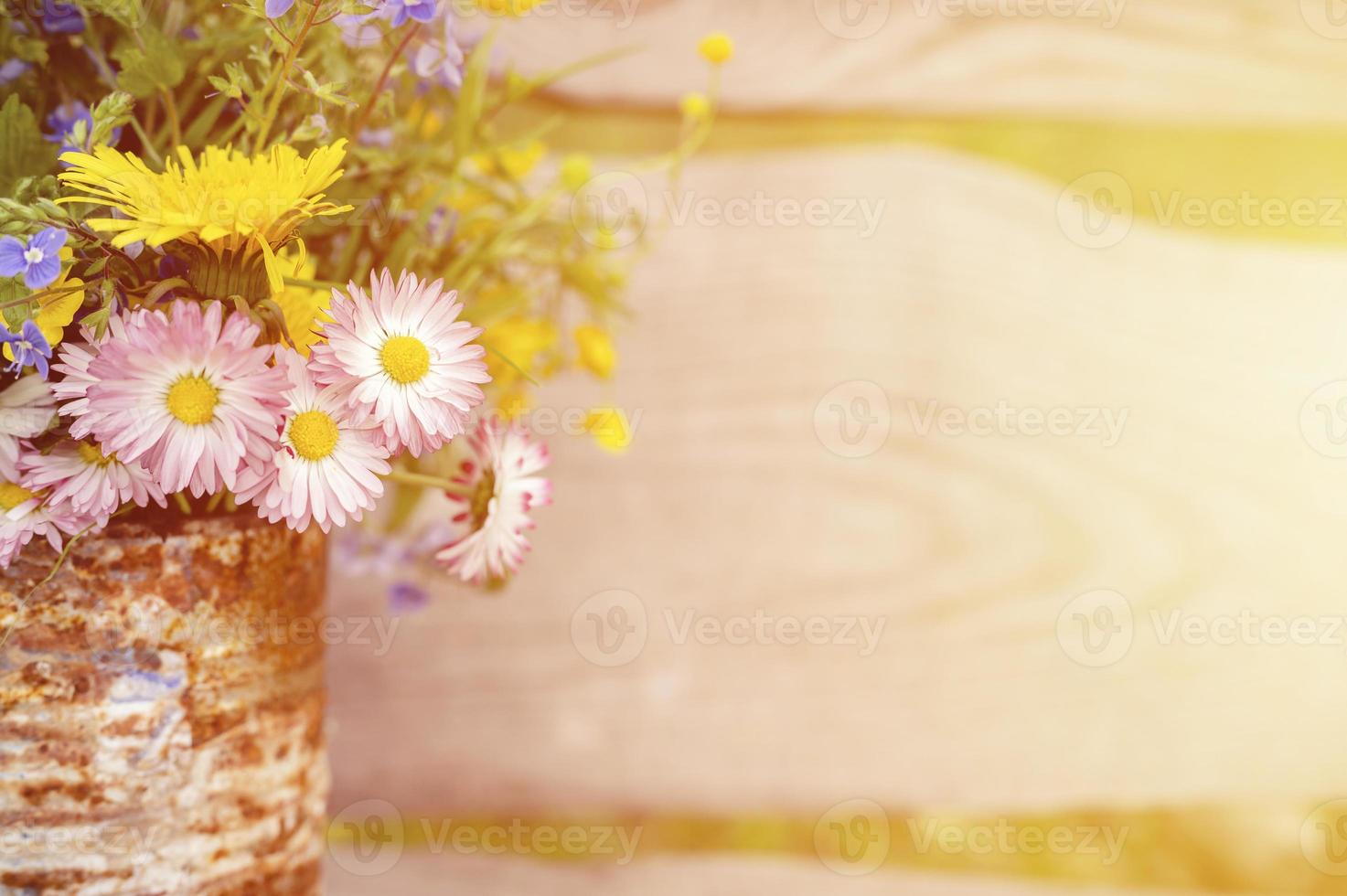 um buquê de flores silvestres de miosótis, margaridas e dentes-de-leão amarelos em plena floração em um frasco rústico foto