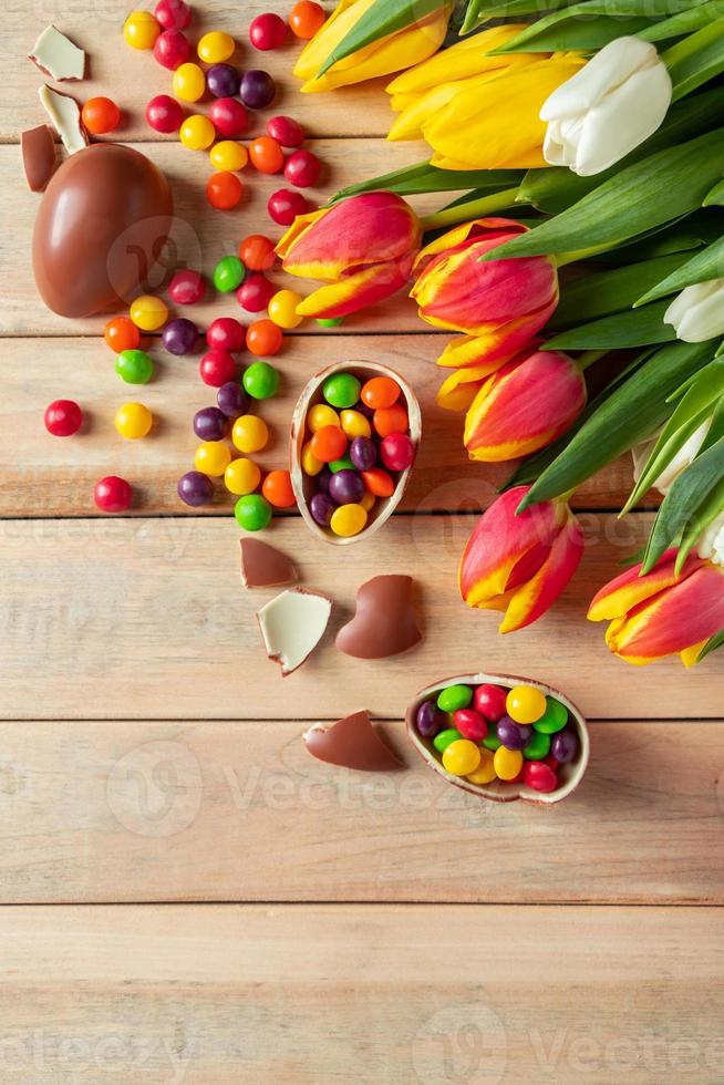 tulipas e ovos de páscoa de chocolate em um fundo de madeira foto