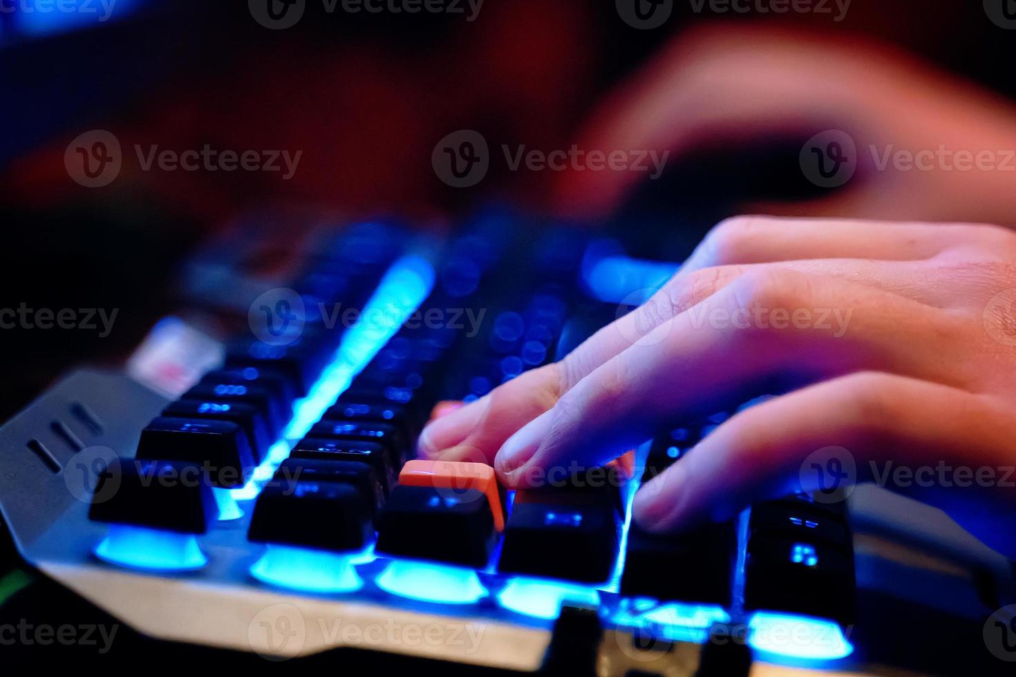 close-up de mãos humanas em um teclado iluminado por néon foto