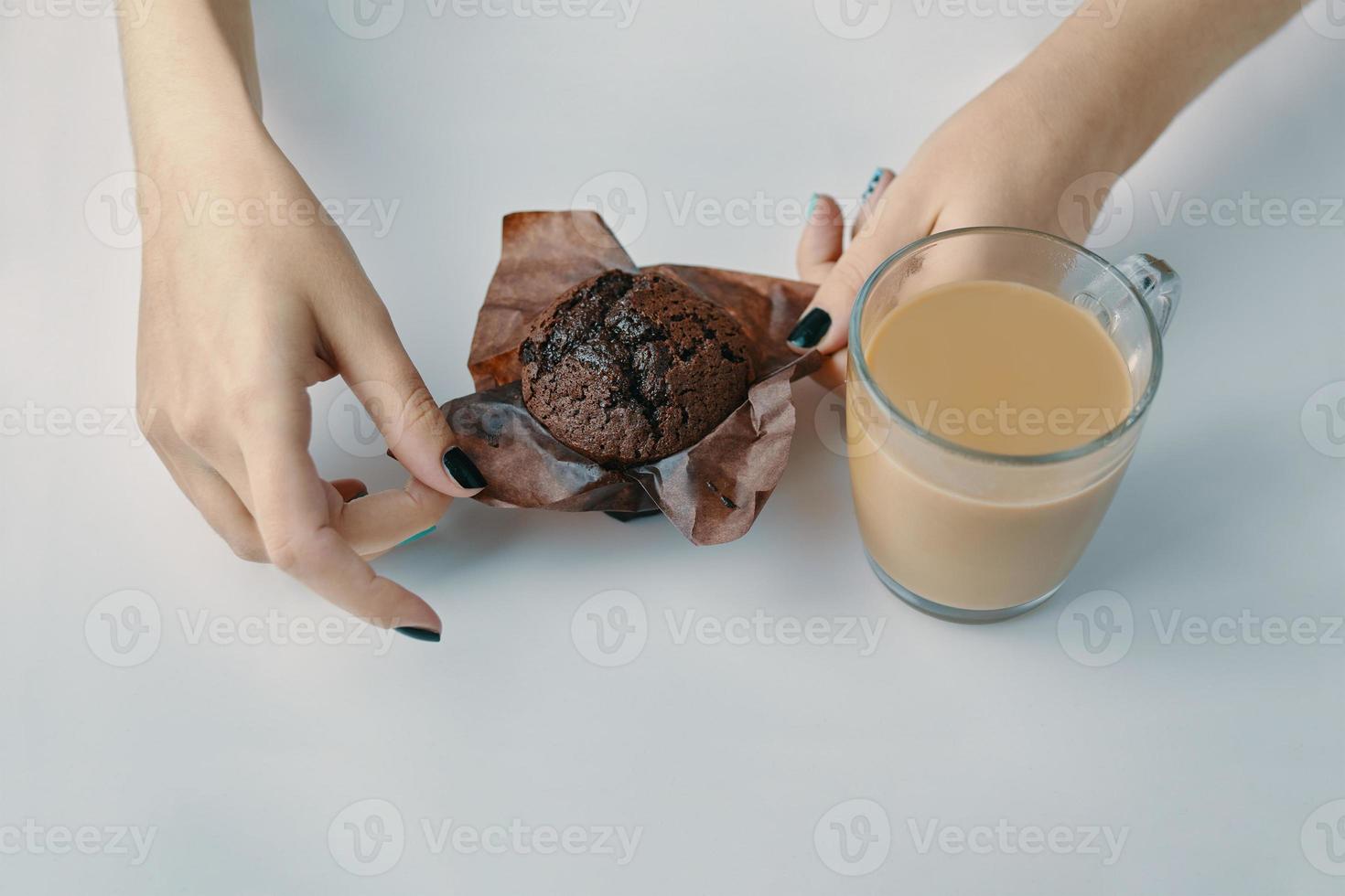 mãos femininas desembrulham um muffin de chocolate foto