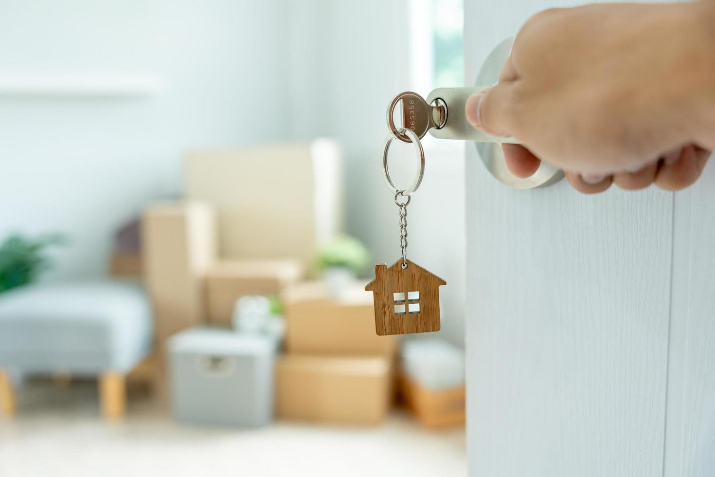 mudança de casa, realocação. a chave foi inserida na porta da nova casa, dentro do quarto havia uma caixa de papelão contendo pertences pessoais e móveis. mudar no apartamento ou condomínio foto