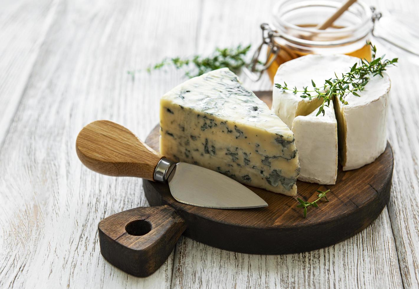 vários tipos de queijo, queijo azul, brie, camembert e mel em uma mesa de madeira foto