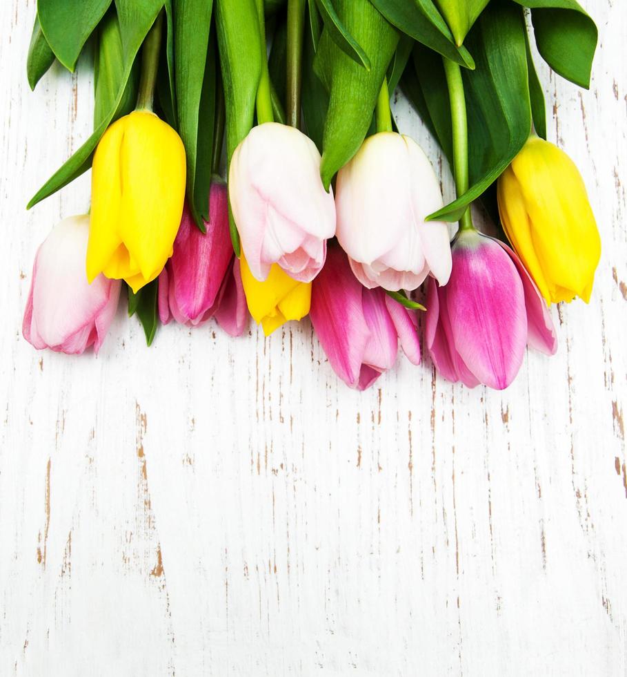 buquê de tulipas rosa e amarelas em um fundo de madeira foto