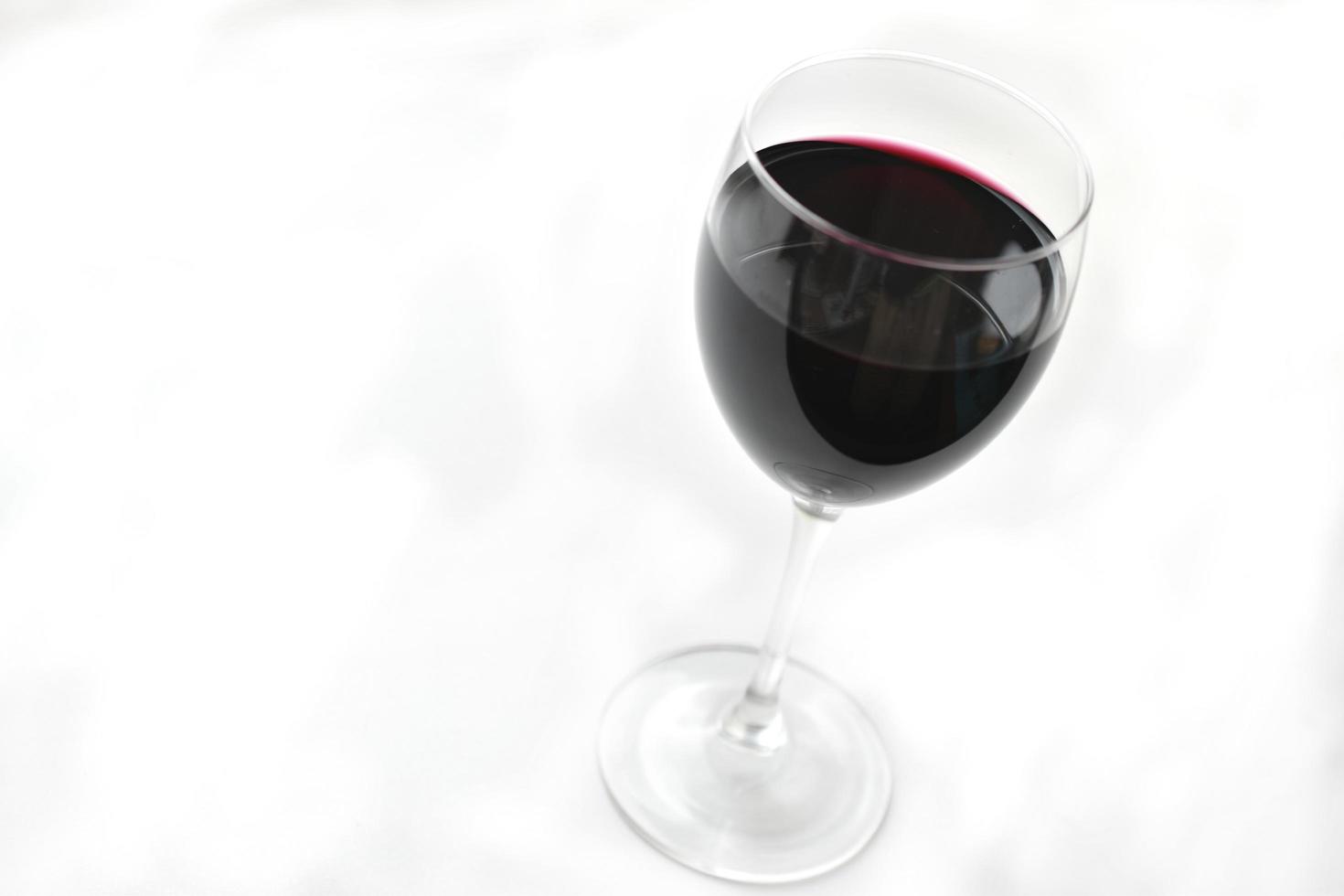 copo grande de vinho tinto em um fundo branco foto