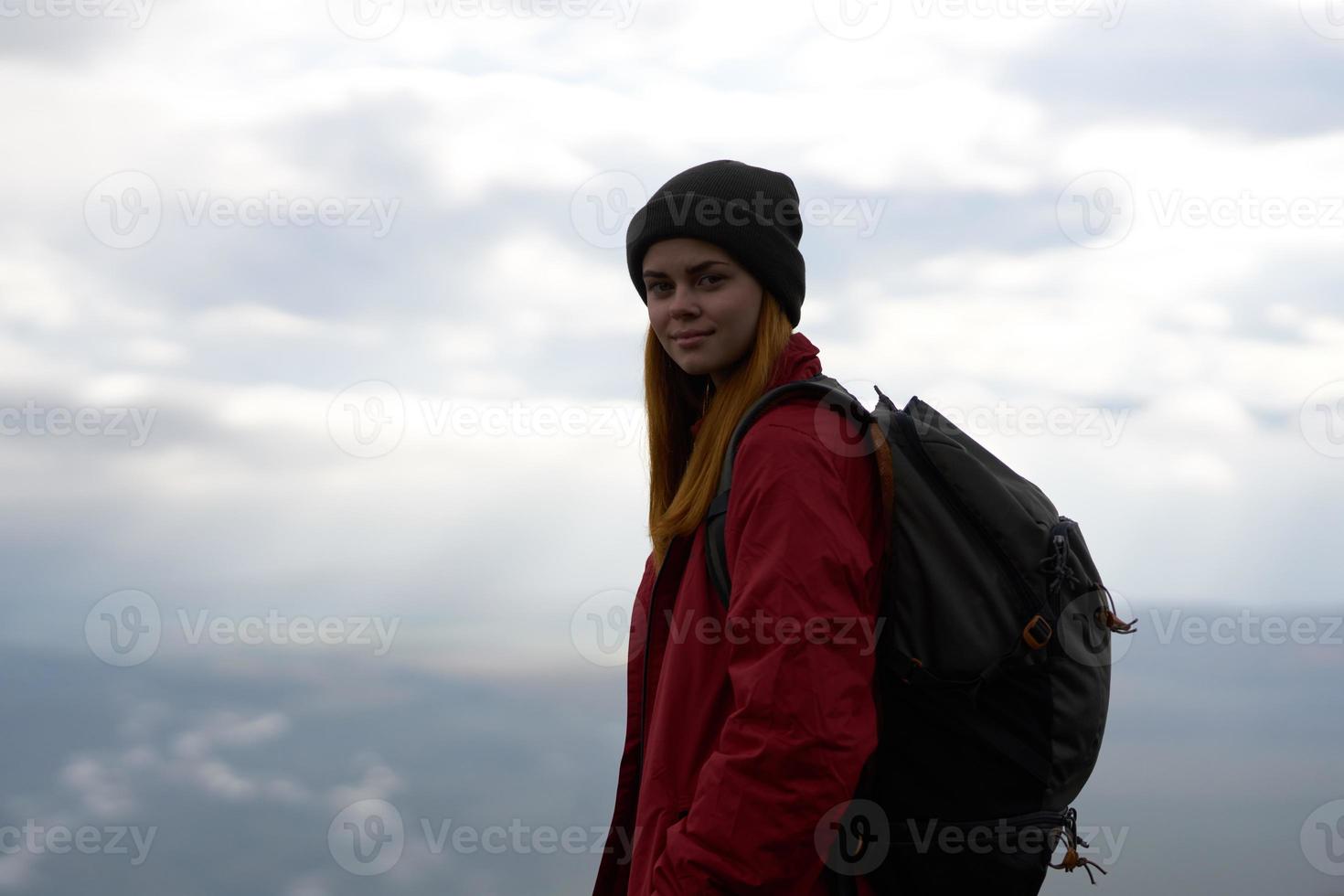 mulher viaja dentro a montanhas com uma mochila dentro a tarde panorama nuvens foto