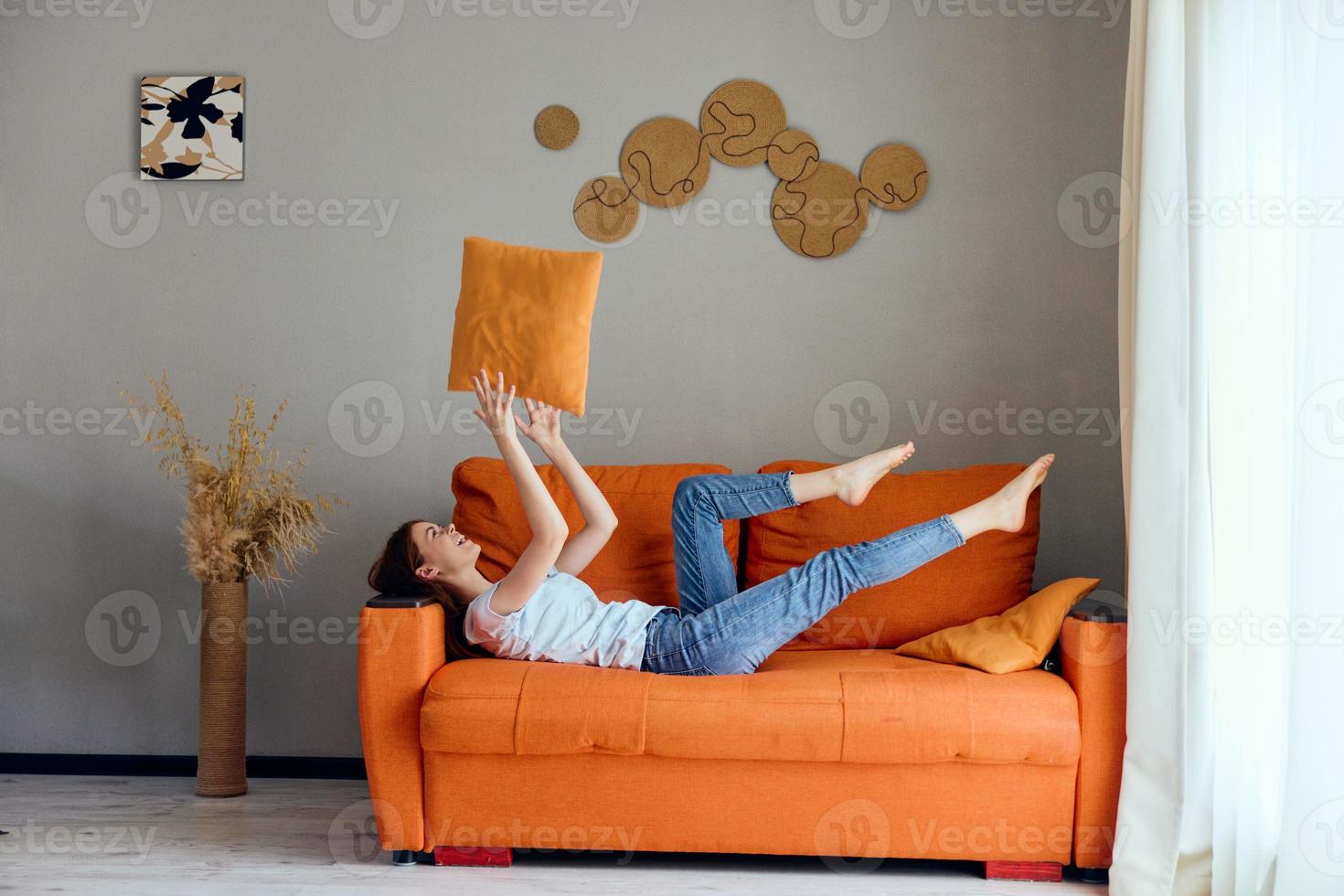 sorridente mulher em a laranja sofá dentro a descansar quarto posando apartamentos foto