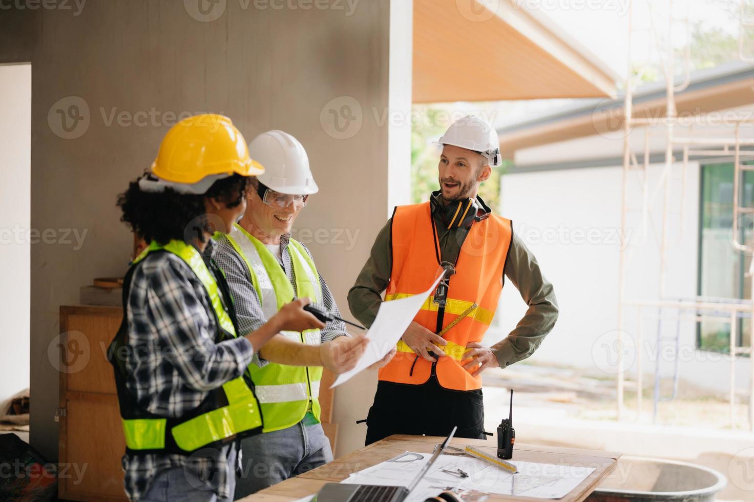 contratante e arquiteto olhando às plano, tábua, computador portátil e falando sobre trabalhando em grande projeto. construção dentro construção processo interior. equipe trabalhos foto