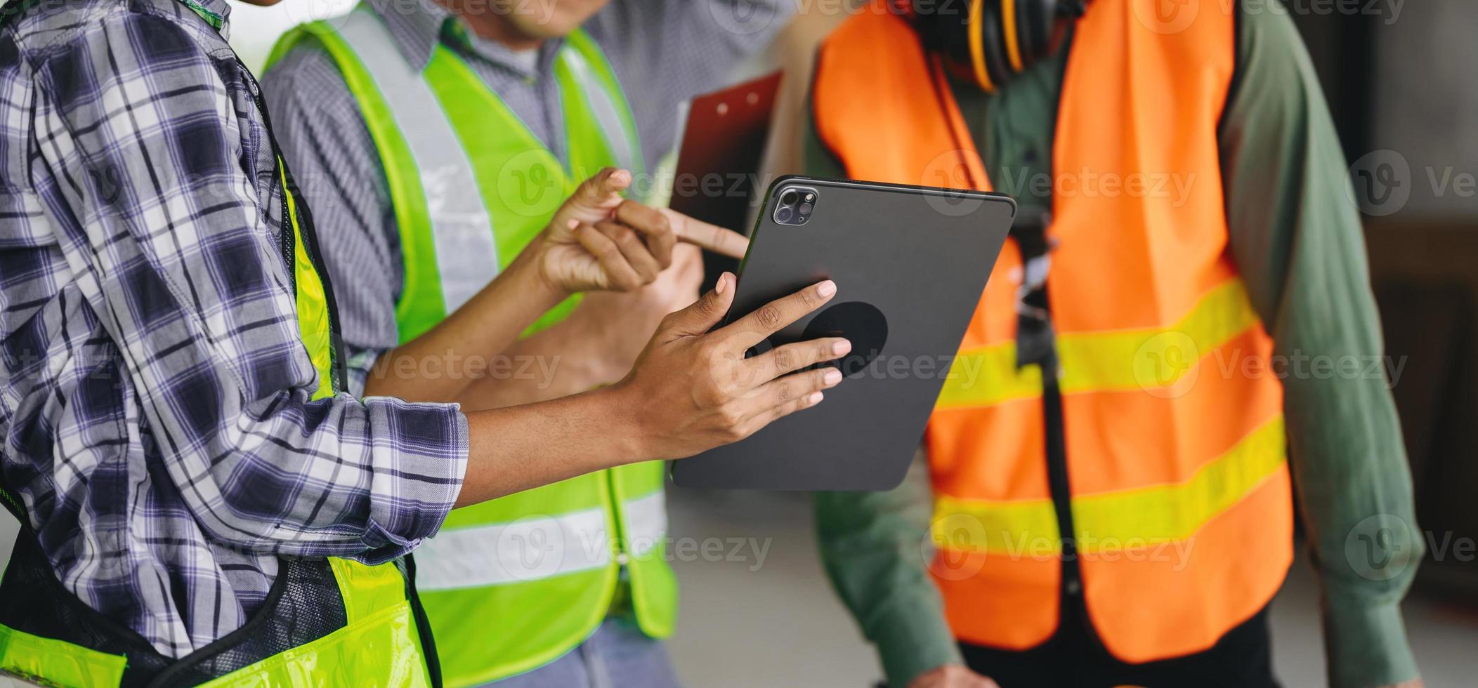 colegas discutindo trabalho de dados e tablet, laptop com no projeto arquitetônico no canteiro de obras na mesa no escritório foto