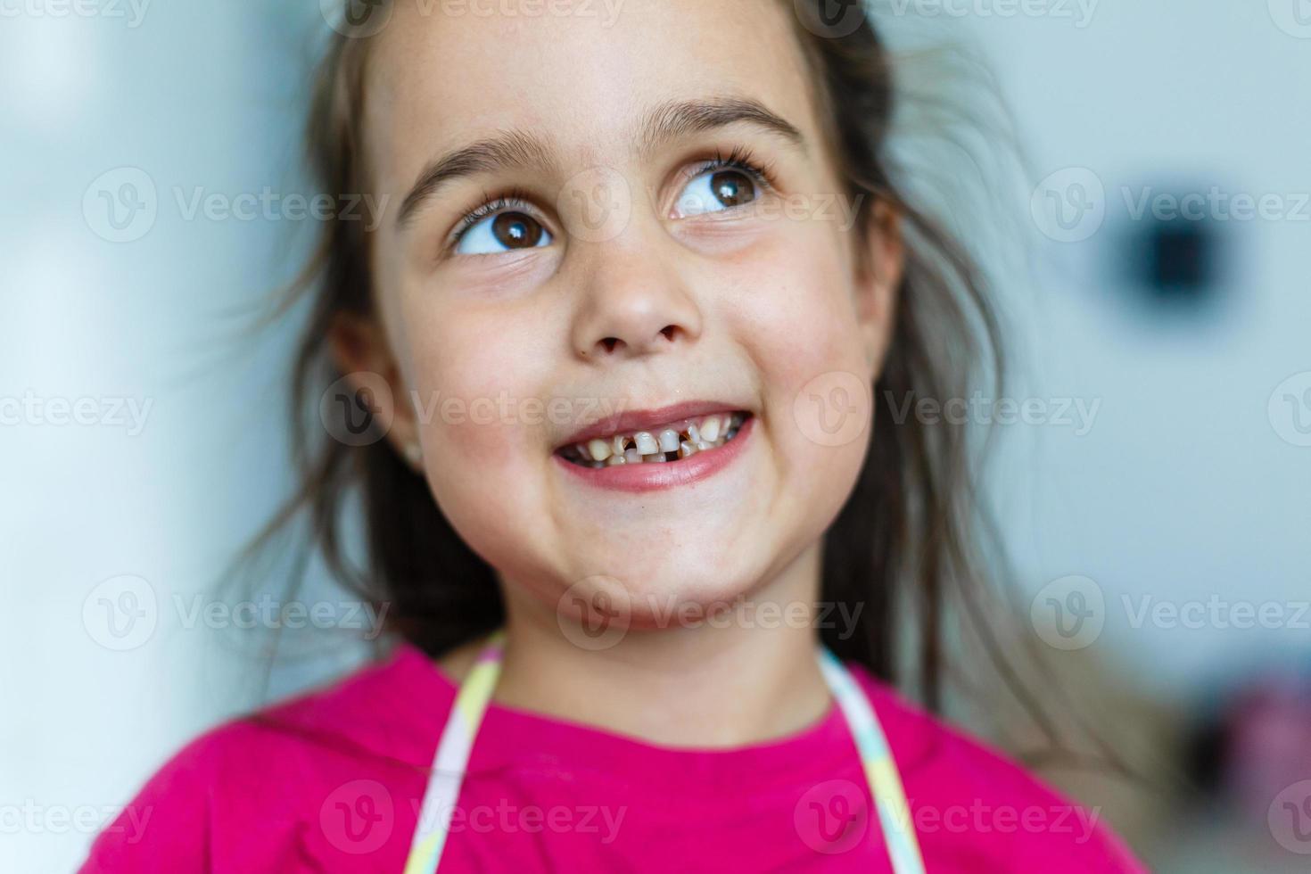 pequeno menina caiu uma bebê dente. criança boca com orifício entre a dentes. raso departamento do campo foto