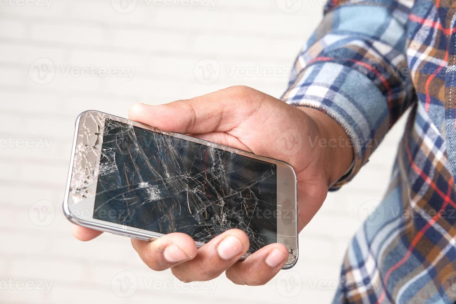 homem segurando a tela do telefone quebrada foto