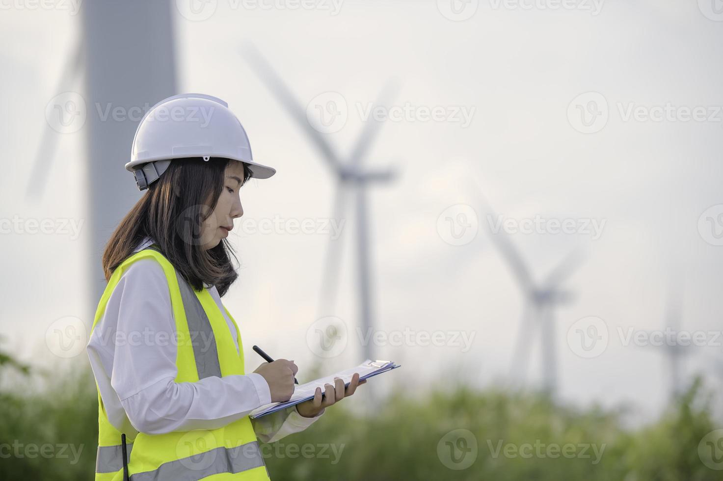 mulheres engenheiras trabalhando e segurando o relatório na estação de gerador de energia de turbina eólica na montanha, tailândia foto