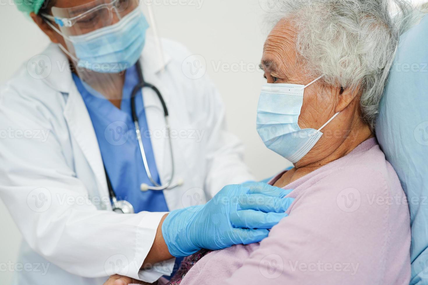 médico em termômetro infravermelho de usuário de ppe para verificar a temperatura da paciente idosa asiática para segurança para proteger o vírus covid 19. foto