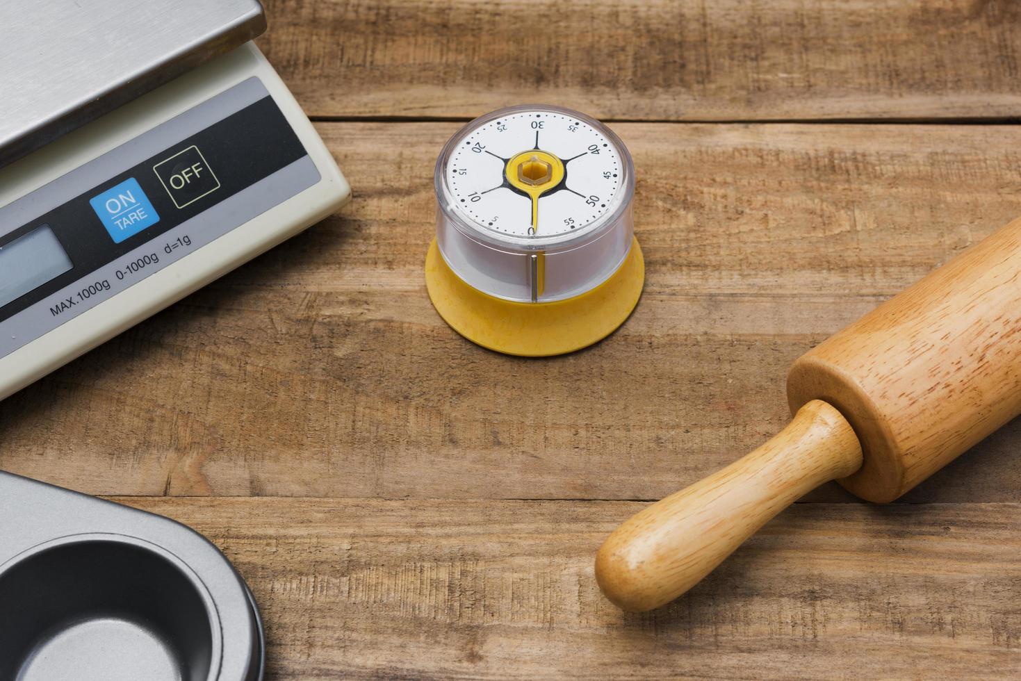 Panificação e utensílios de cozinha com cronômetro de cozinha, balança e molde de cozinha em uma mesa de madeira foto