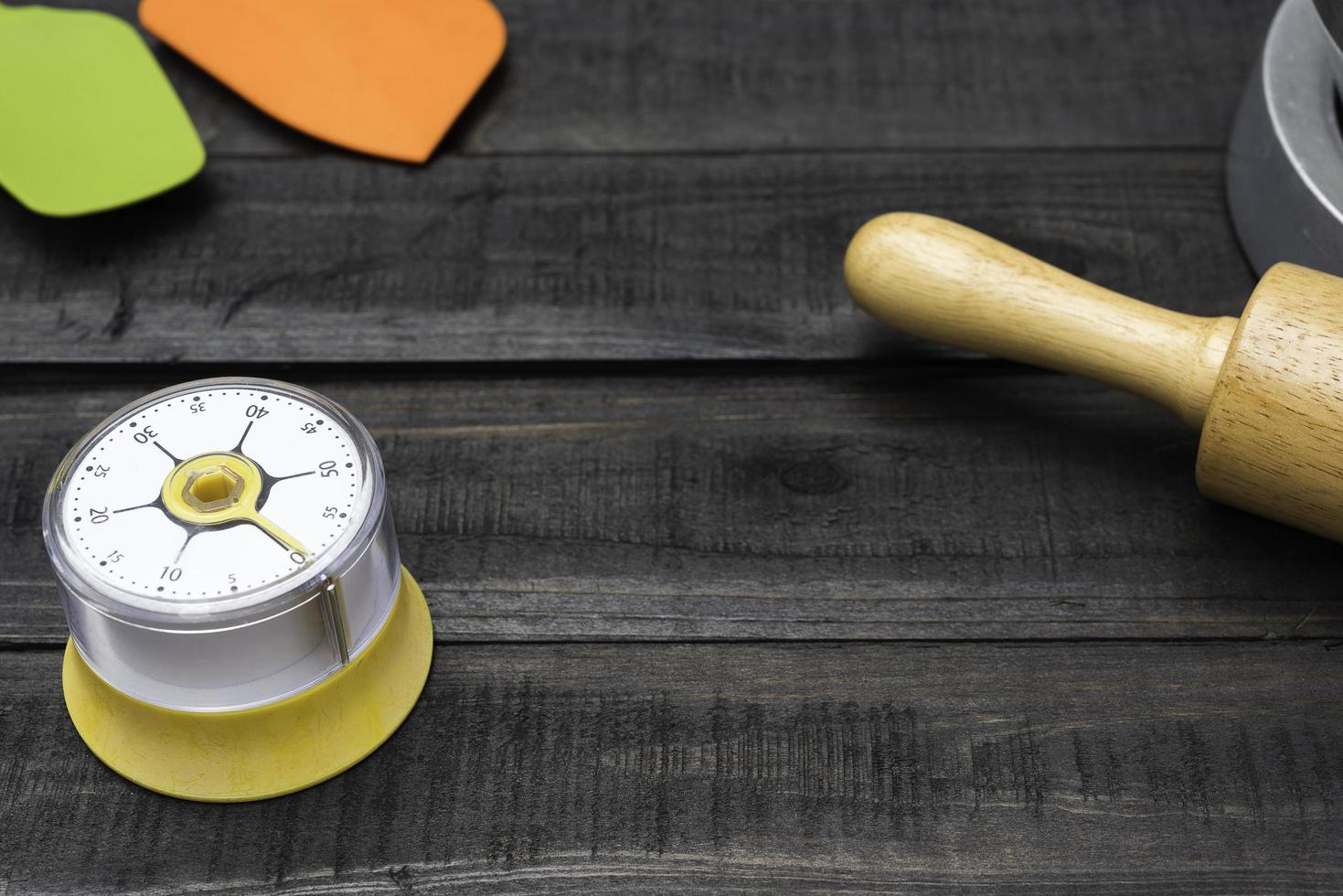 Panificação e utensílios de cozinha com cronômetro de cozinha em uma mesa de madeira foto