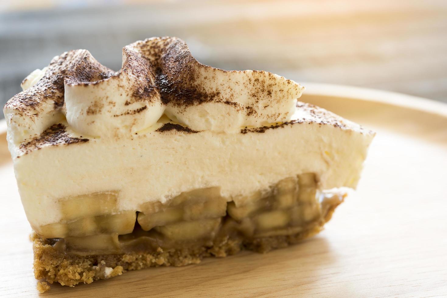 torta de banoffee com chocolate em pó em um prato de madeira foto