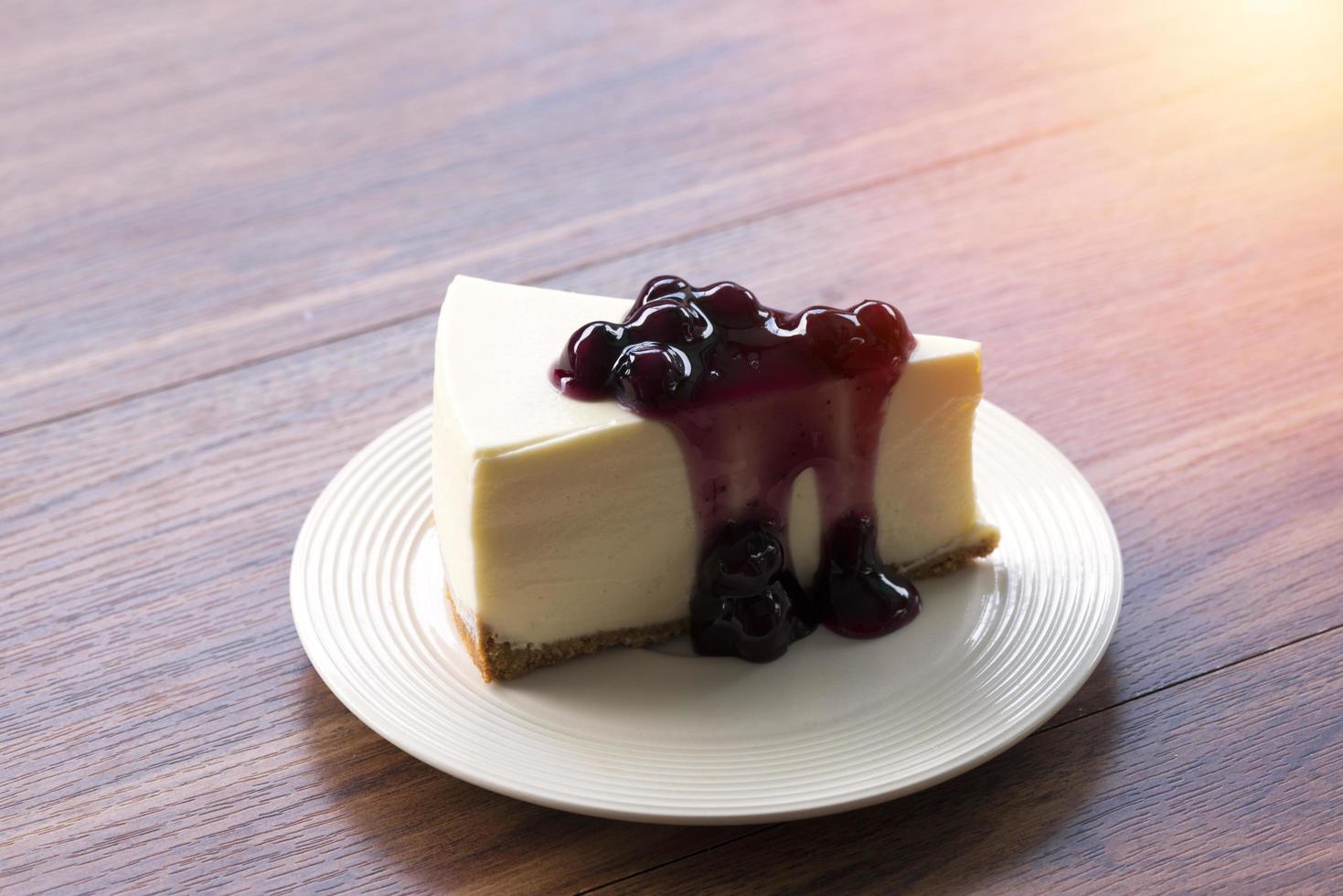 Cheesecake de creme de mirtilo em um prato branco sobre uma mesa de madeira foto