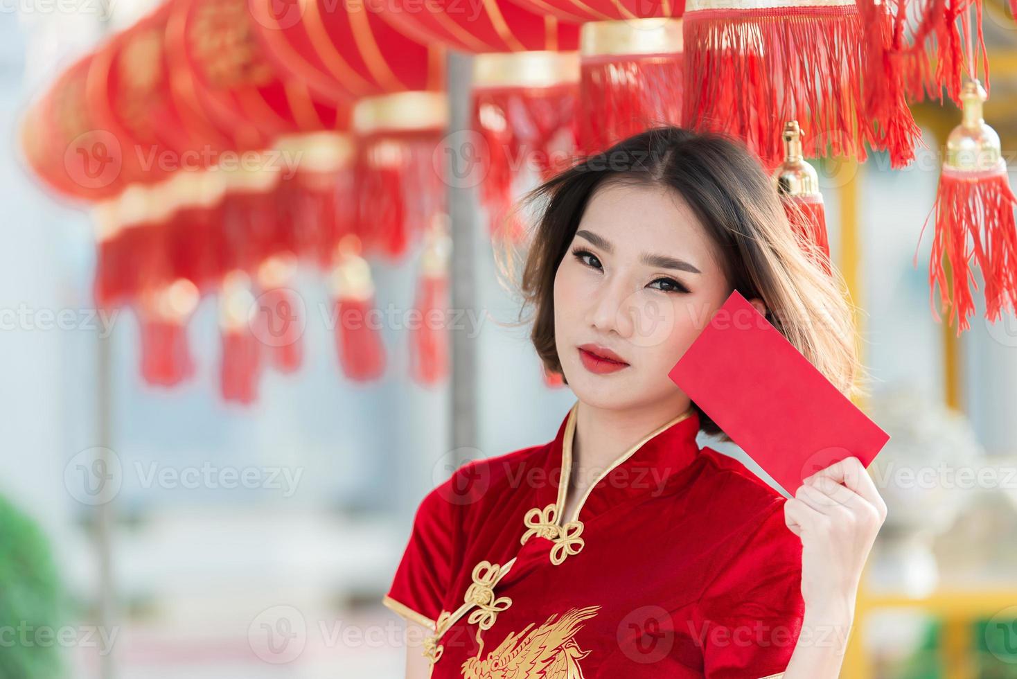 retrato lindo ásia mulher dentro cheongsam vestido, tailândia gente, feliz chinês Novo ano conceito, feliz ásia senhora dentro chinês tradicional vestir segurando uma vermelho envelope foto