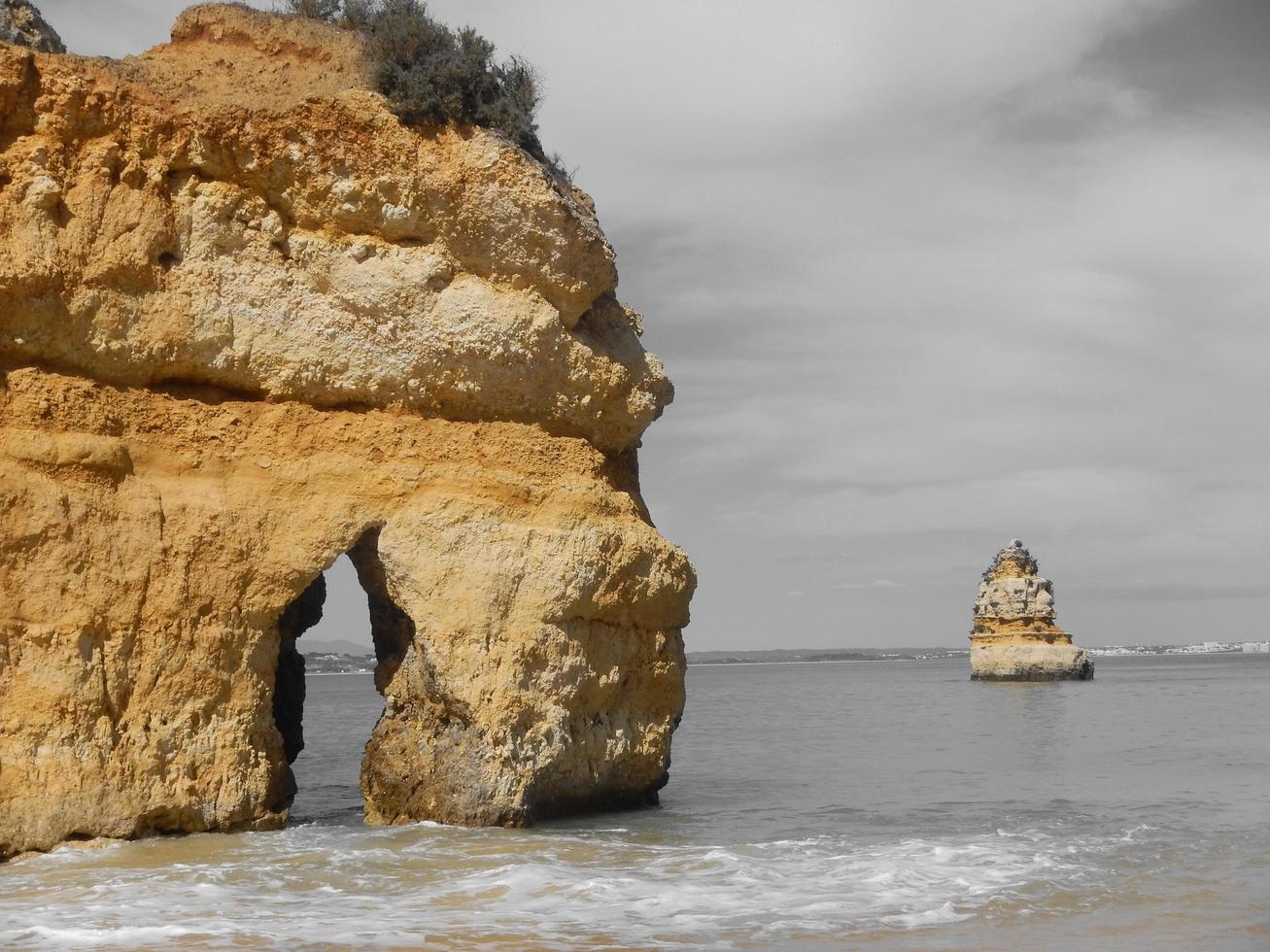 uma grande rocha na areia da praia foto