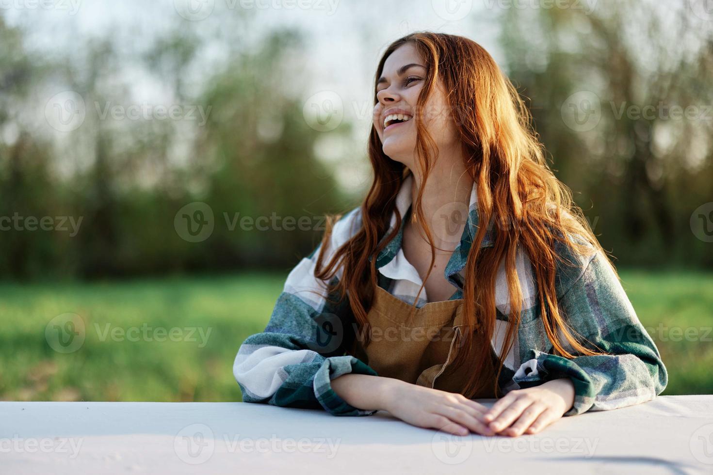 uma lindo mulher risos com uma cheio de dentes sorrir e goza descansando dentro uma verde parque em uma verão tarde dentro a configuração luz solar. a conceito do uma saudável estilo de vida e a bati do autocuidados foto