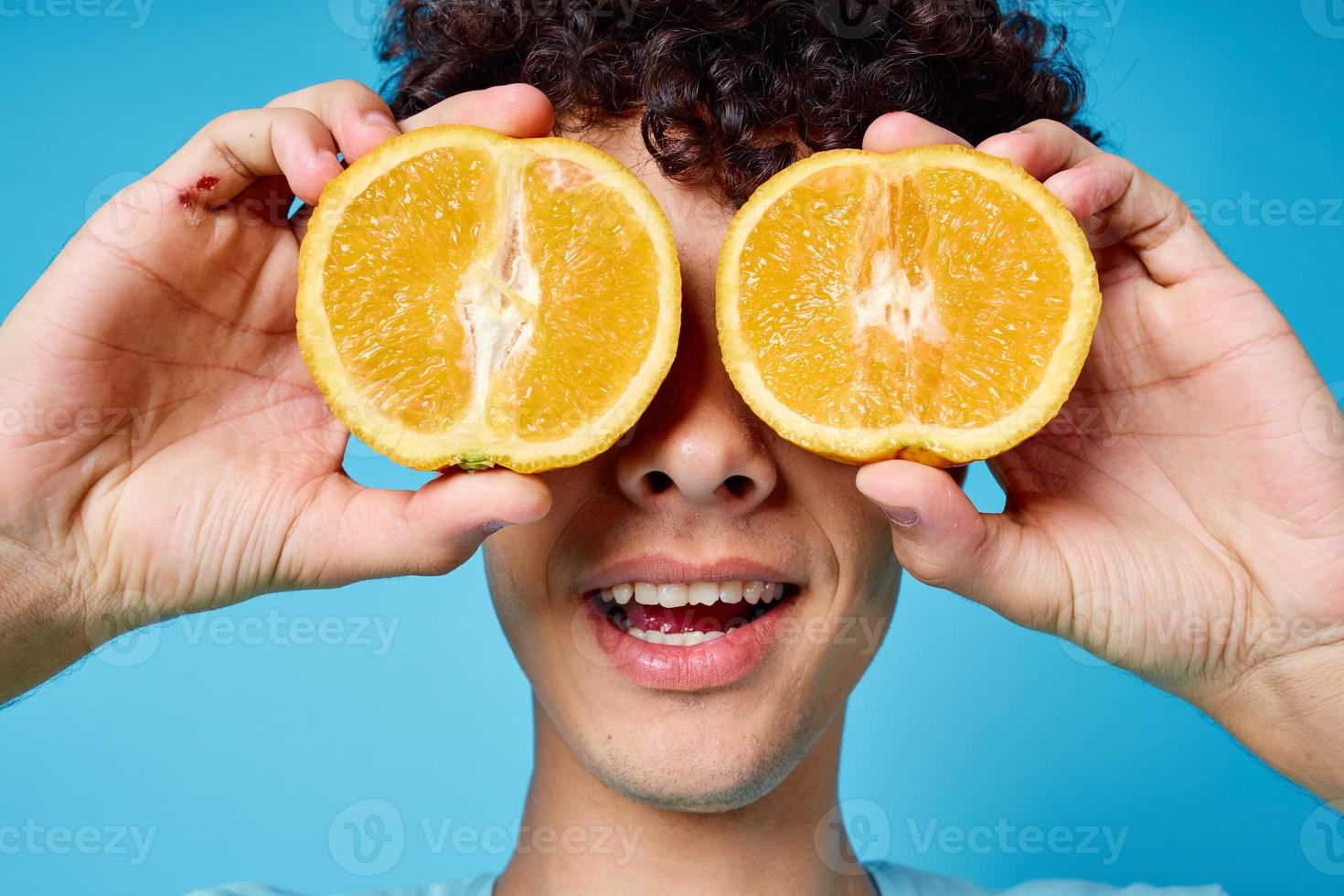 alegre cara segurando laranjas perto dele olhos fechar-se azul fundo foto