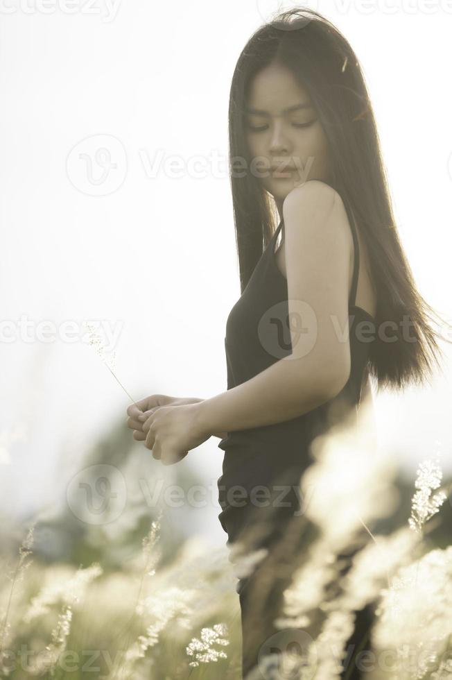 retrato do lindo ásia mulher às Relva campo em pôr do sol foto