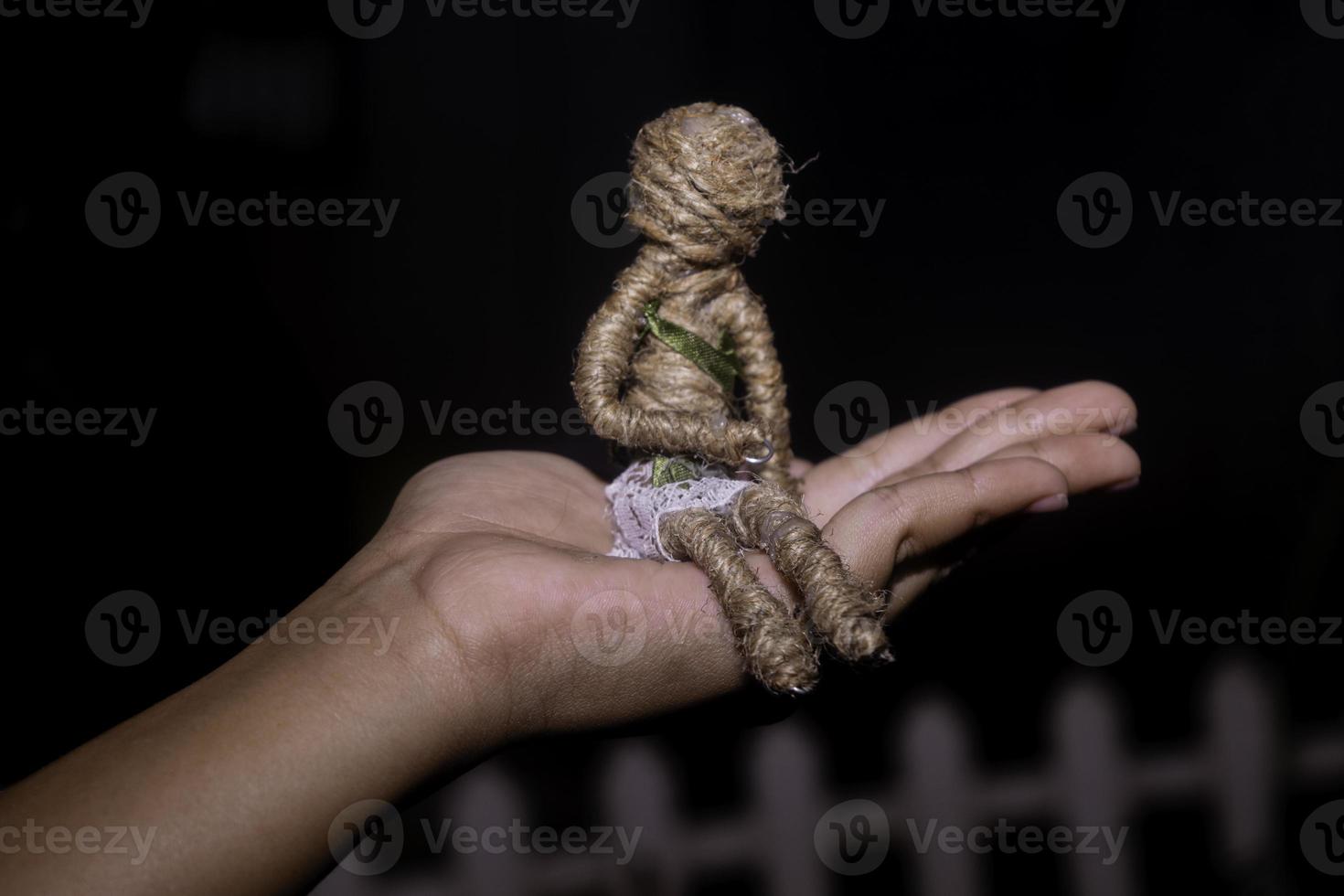 mão segurando uma corda boneca em uma Preto background foto