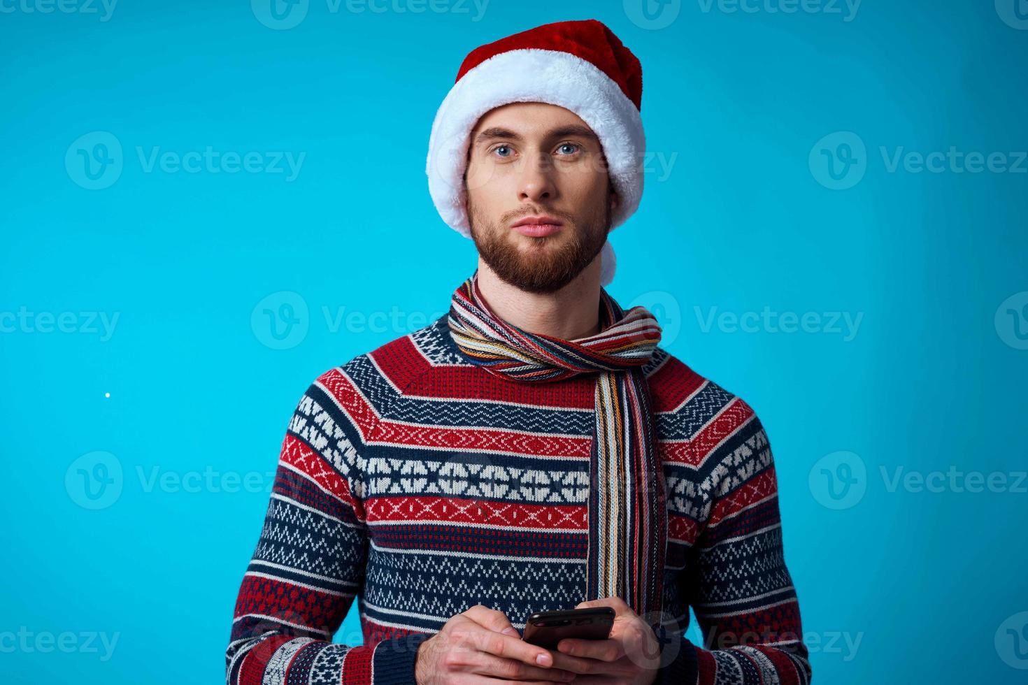 alegre homem com uma telefone dentro mão feriado Natal tecnologia azul fundo foto